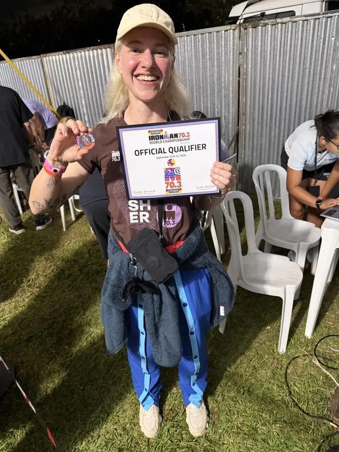 Zoe holding her Ironman 70.3 World Championship Official Qualifier certificate, smiling, Brasilia 2026
